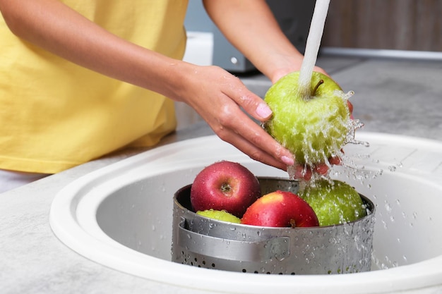 Woman washing fresh apples in kitchen sink closeup