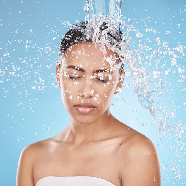 Foto donna che lava i capelli o la cura della pelle con spruzzi d'acqua su sfondo blu studio in sanità benessere dermatologia toelettatura o pulizia igienica modello di bellezza bagnato o gocce d'acqua nella cura dei capelli della doccia del bagno