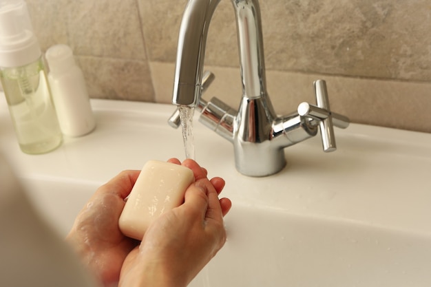 Woman washing hands in bathroom sink with soap