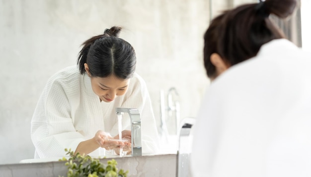 浴室の鏡の前に立っている女性が手を洗っています