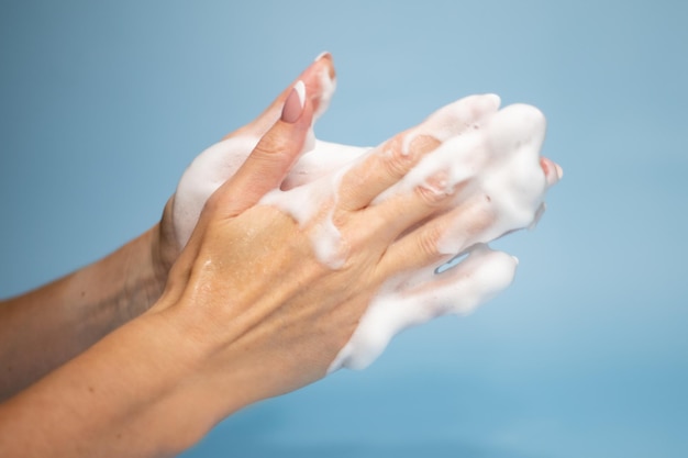 Woman washing hands with soap on color background