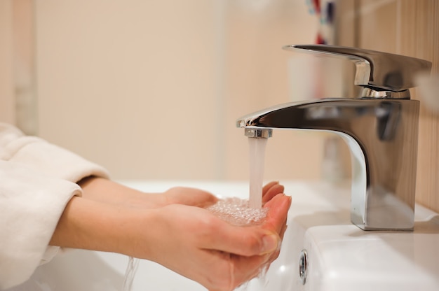 A woman washing her hands in the sink.