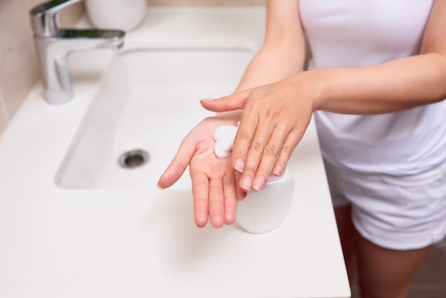 Una donna che si lava le mani con una schiuma di sapone.