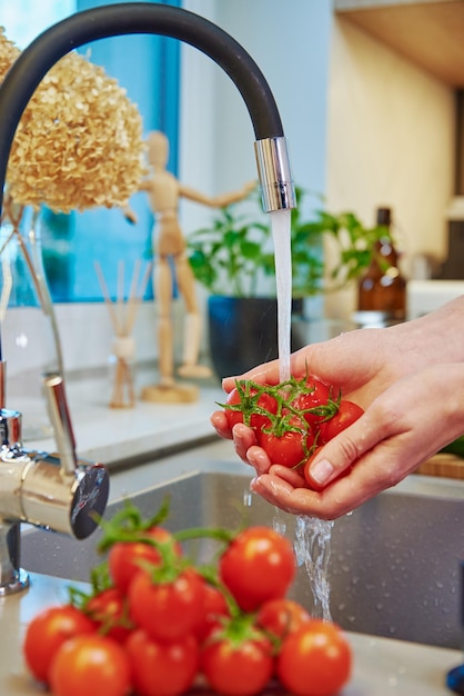 Foto donna che lava i pomodori al lavandino della cucina