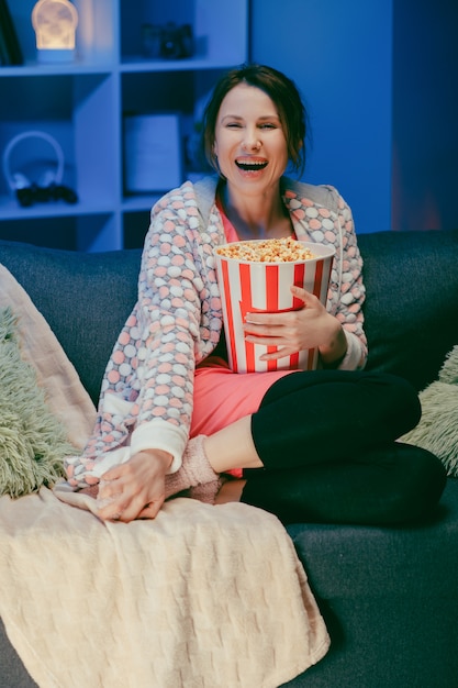 woman watching comedy film in home. woman sitting on sofa and watching TV. Concept of entertainment.