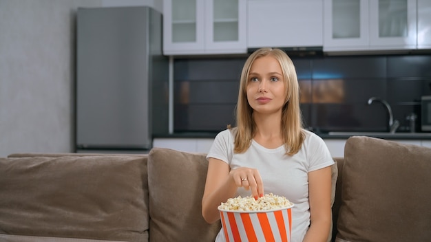 Woman watching fillm, smilling and eating popcorn.