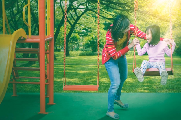 Woman watching her daughter swinging joyfully