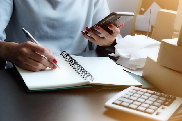 Photo woman watching mobile screen and write record or note of data report prepare document for present