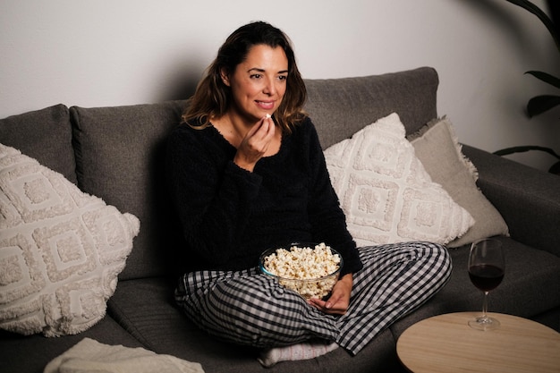 Foto donna che guarda un film da sola a casa con i popcorn e che si concentra sul cinema concettuale