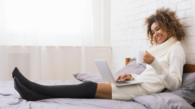 Женщина смотрит видео на ноутбуке и пьет кофе.