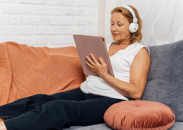 Photo woman watching a video on a tablet while listening the audio on headphones