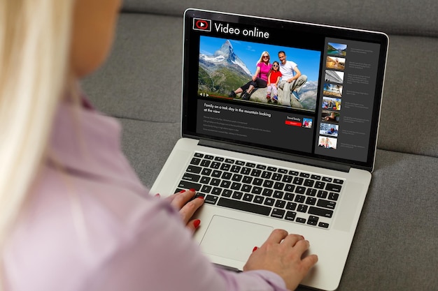 Женщина смотрит видео онлайн на ноутбуке.