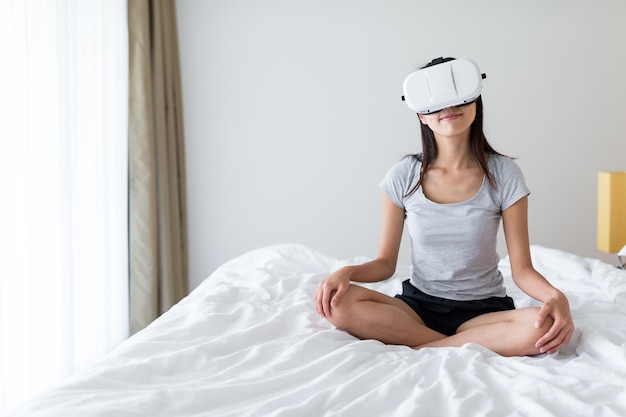 Woman watching virtual reality device on bed