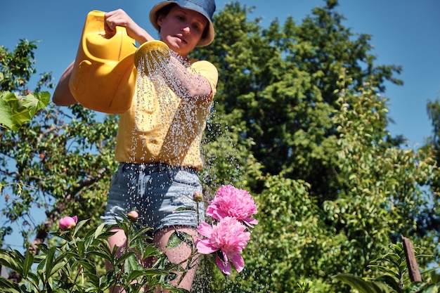 庭の花に水をまく女性