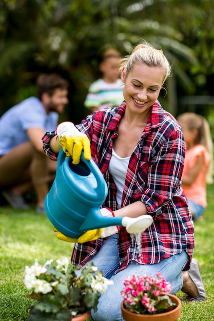 Woman watering flowers on grass at yard