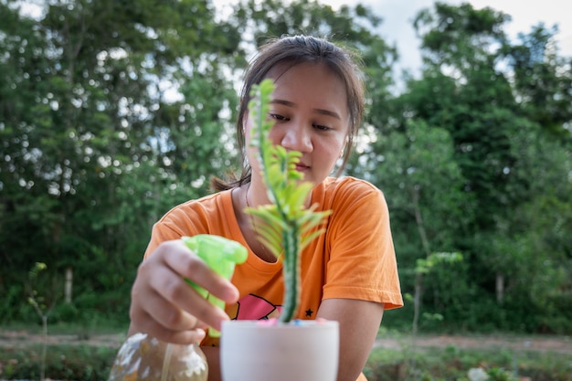 Woman watering ornamental plants by spraying water to add freshness.