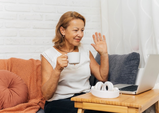 Woman waving to friends while having a video call