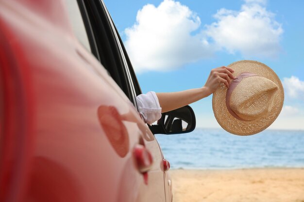 Woman waving from car on beach closeup summer vacation trip