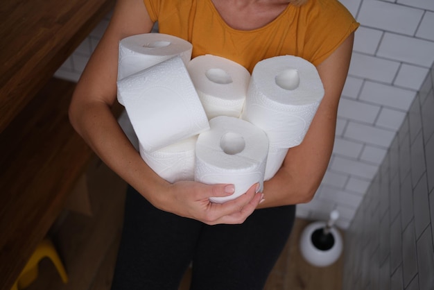 Woman in the wc holds many rolls of toilet paper