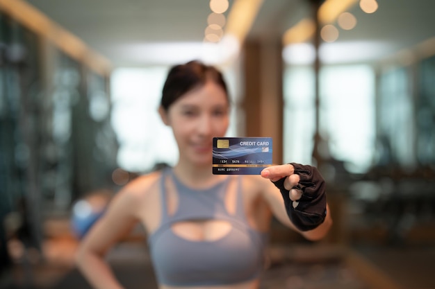 Foto la donna indossa abbigliamento sportivo blu mostra carta di credito paga l'iscrizione alla palestra