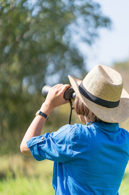 Foto il cappello di usura della donna e tiene il binocolo nel campo di erba