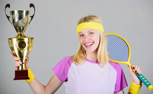 Woman wear sport outfit. First place. Sport achievement. Celebrate victory. Tennis champion. Athletic girl hold tennis racket and golden goblet. Win tennis game. Tennis player win championship.