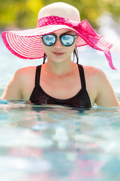 Woman wear sunglasses in pool.