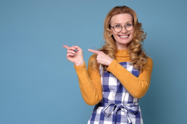 Photo woman wearing apron smiling and looking at camera pointing with two hands