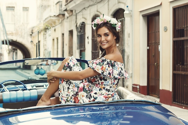 Woman wearing beautiful dress and retro convertible car at Havana city