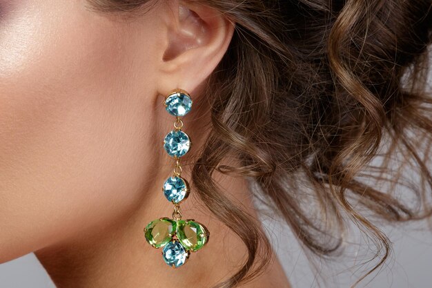 Woman wearing beautiful and expensive earrings with colorful gems