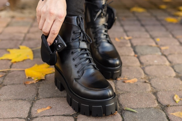 A woman wearing black boots is cleaning her shoes.