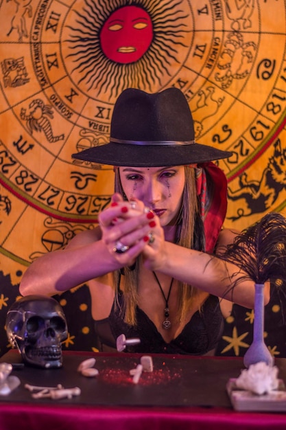 женщина в черной шляпе и руническими буквами, написанными на ее лице, бросает руны, чтобы прочитать судьбу