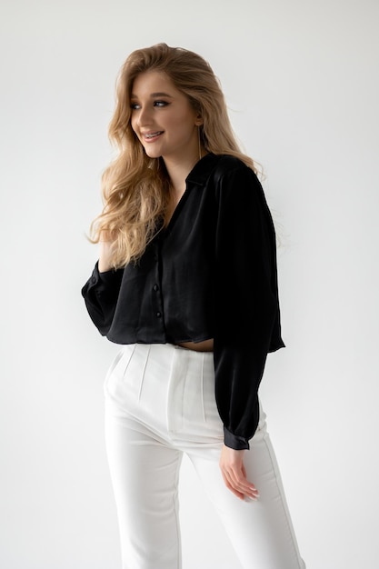 A woman wearing a black long sleeve top with white pants and a black top