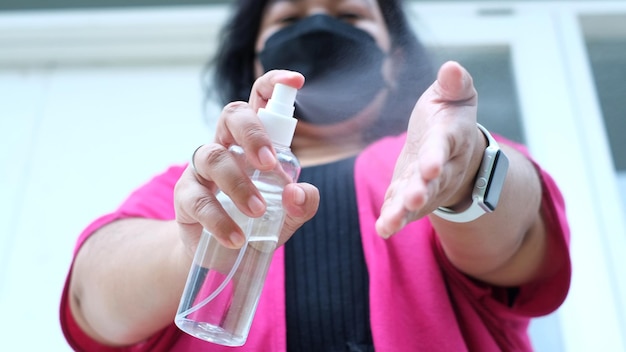 Foto una donna che indossa una maschera nera spruzza disinfettante per le mani
