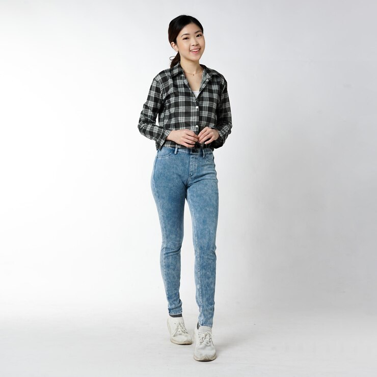 Photo 흑백 체크무늬 셔츠와 청바지를 입은 여성이 흰색 배경 앞에 서 있습니다.