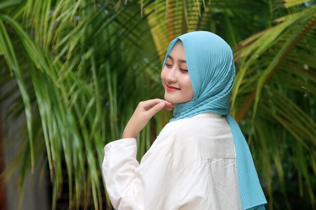 A woman wearing a blue hijab and a white shirt