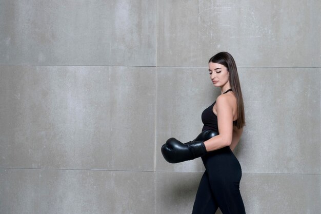 Photo woman wearing boxing gloves while walking against wall