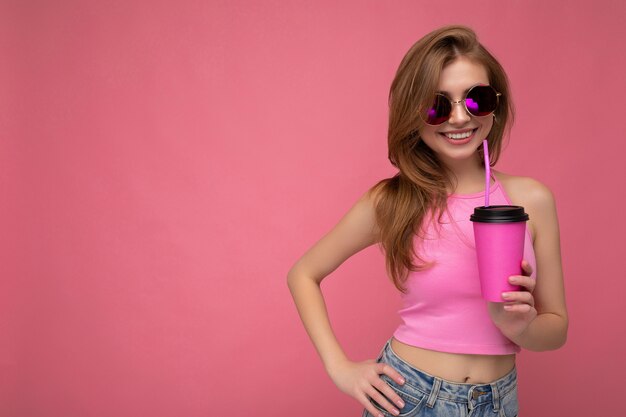 woman wearing casual stylish clothes isolated over colorful wall holding paper cup drinking coffee . empty space