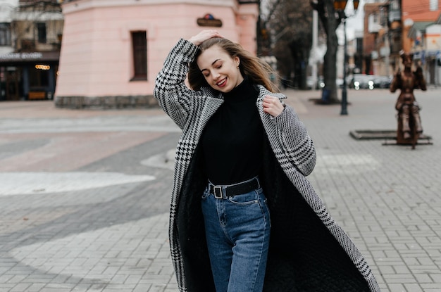 Woman wearing a coat and jeans walking down the street