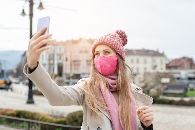 電話でselfieを作るコロナマスクを着ている女性