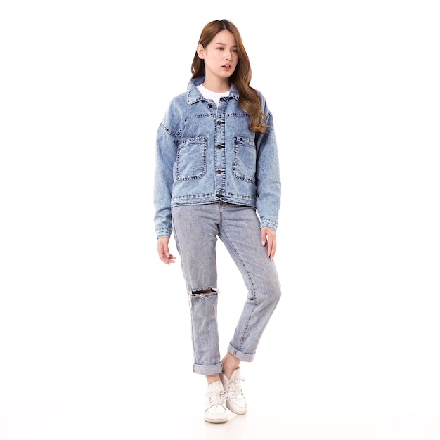 A woman wearing a denim jacket and white sneakers stands in a white background.