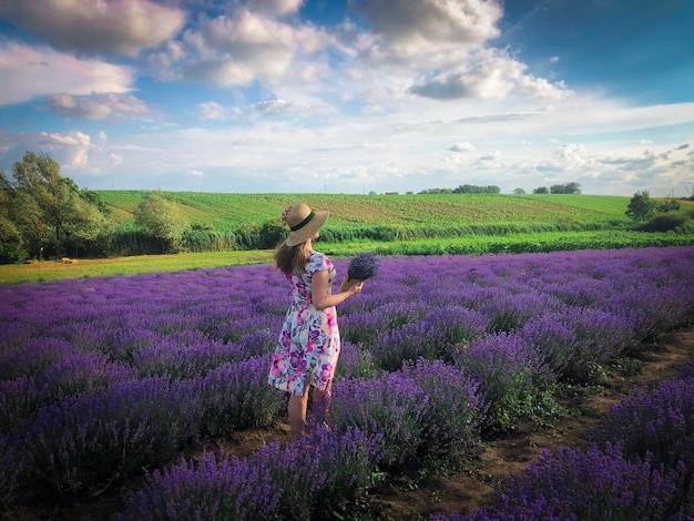 Foto donna con vestito e cappello in un campo di lavanda