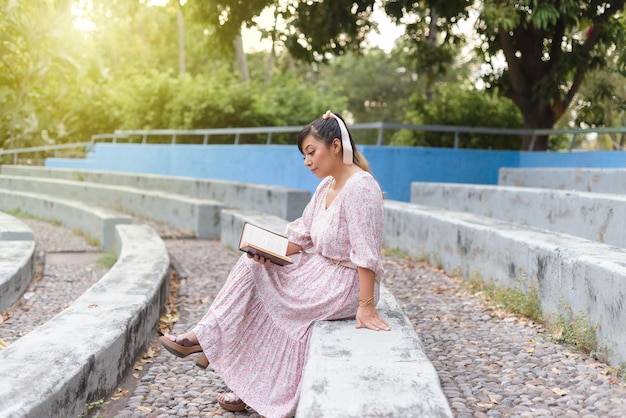 Woman wearing dress reading a book in a park