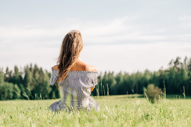 Woman wearing dress sitting on green grass field