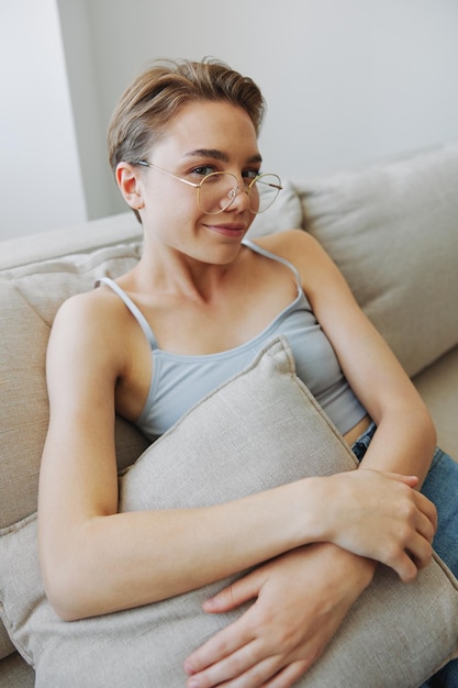 A woman wearing eyeglasses sits on a couch and looks at the camera Vision problems High quality photo