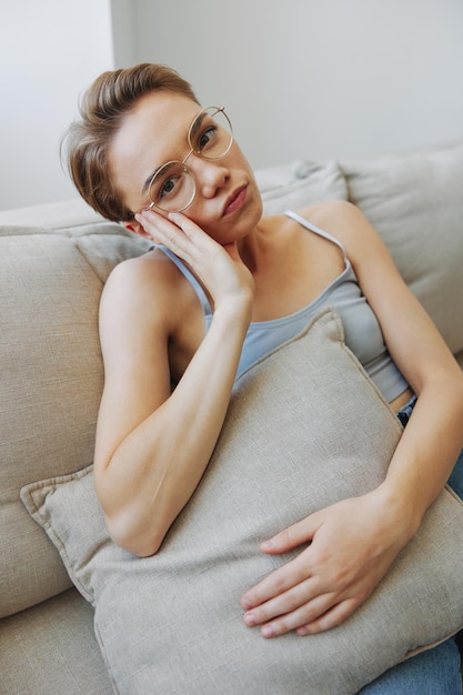 Photo a woman wearing eyeglasses sits on a couch and looks at the camera vision problems