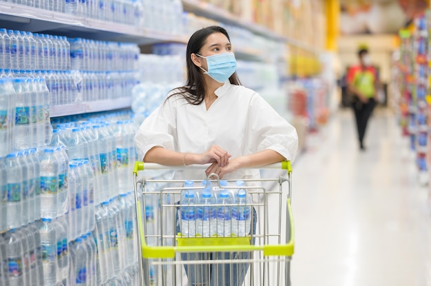 Donna che indossa la maschera per il viso acquisto nel supermercato