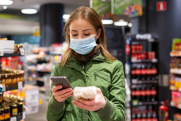 写真 店で顔のマスクを着ていると彼女の電話を見て女性