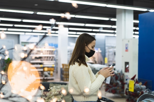 店内でマスクと保護手袋をかぶった女性が今日の人々のライフスタイルコンセプトで電話を使用しています