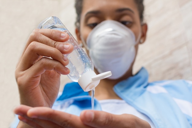 Woman wearing face mask and putting alcohol gel on